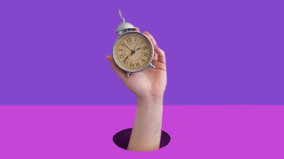Purple background with a hand and alarm clock Hand holding up an alarm clock in front of a purple background